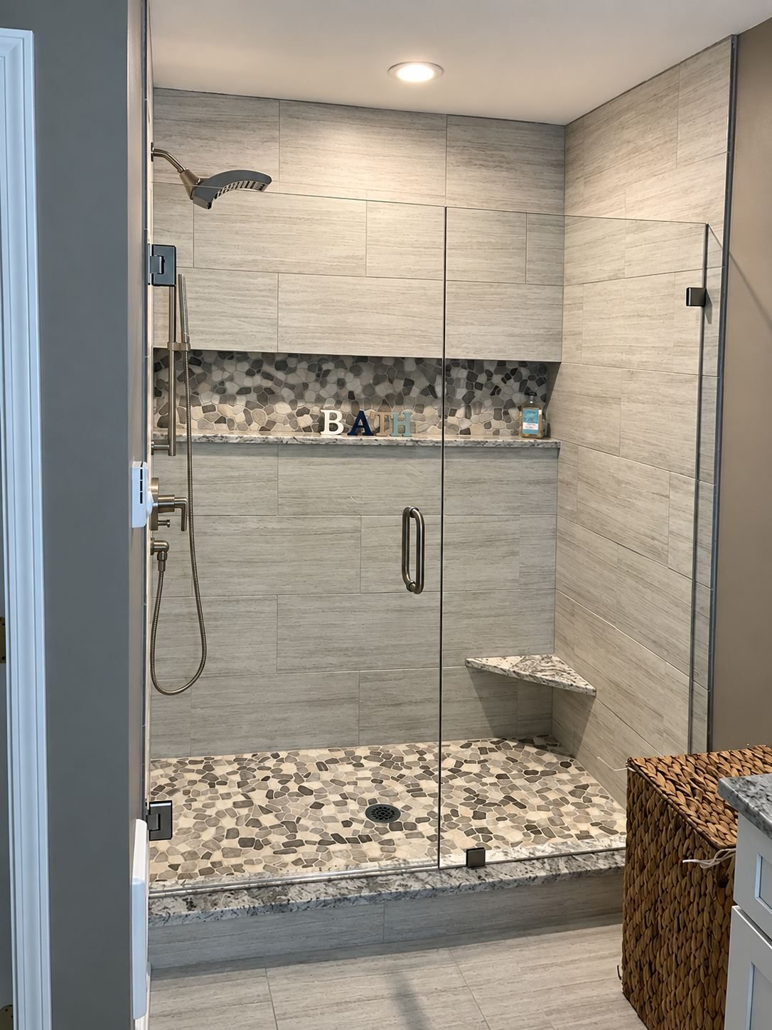 Custom tile shower with pebble floor and accent niche