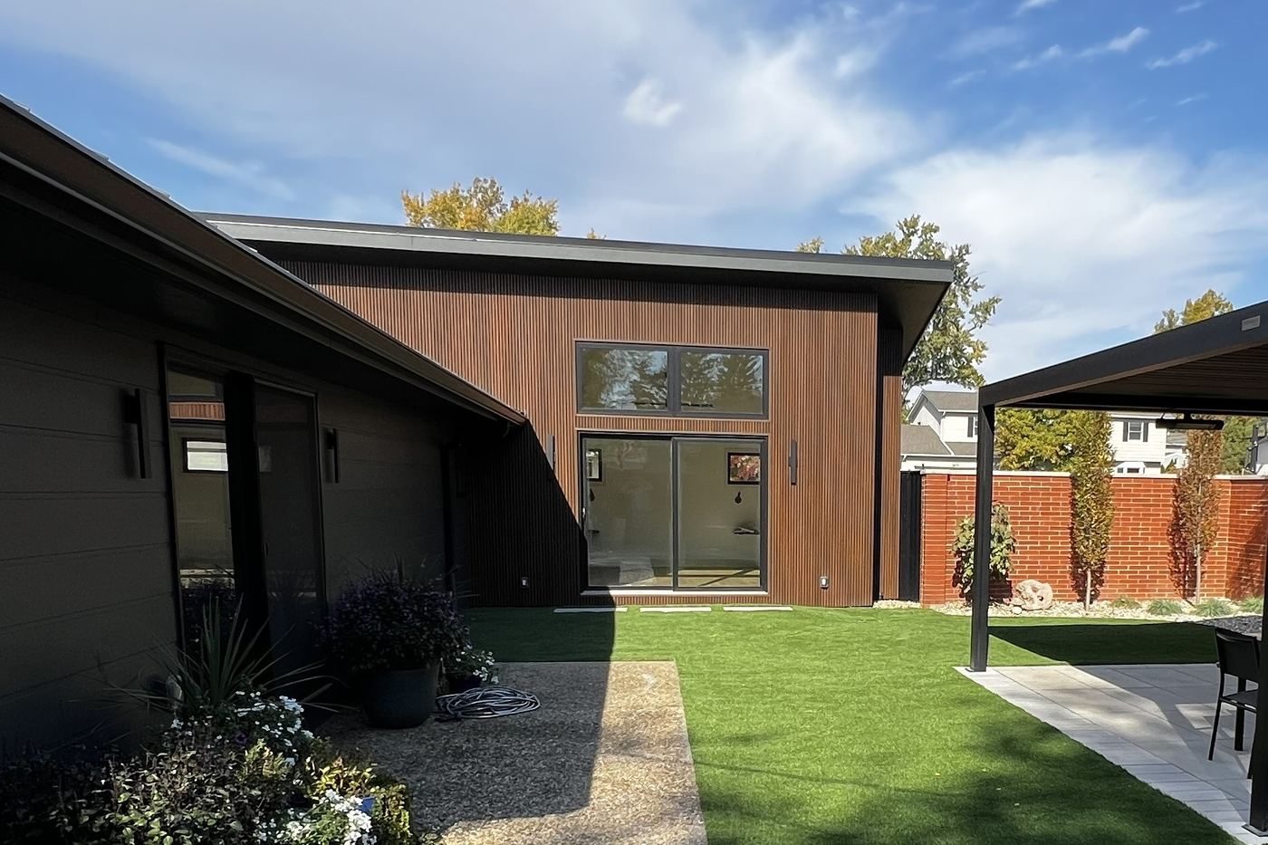 Finished modern home addition with wood siding and covered patio