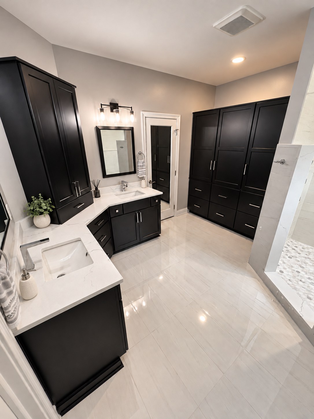 Primary bathroom with black cabinetry, corner vanity, and linen tower