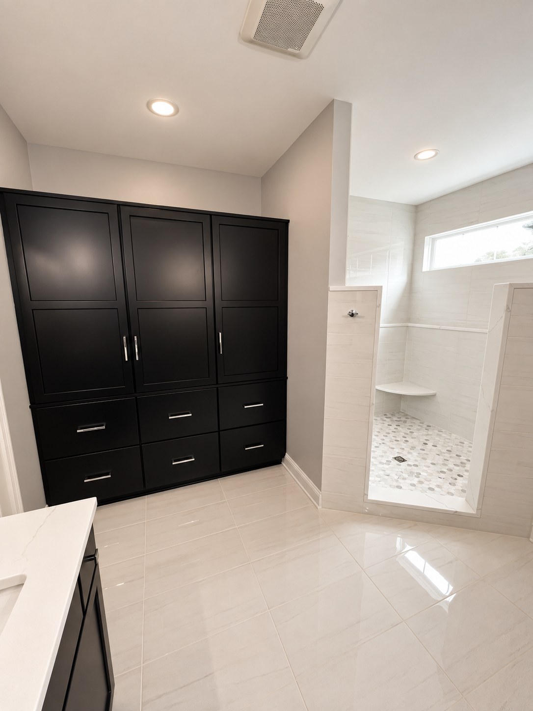 Black linen cabinet beside the walk-in shower entry