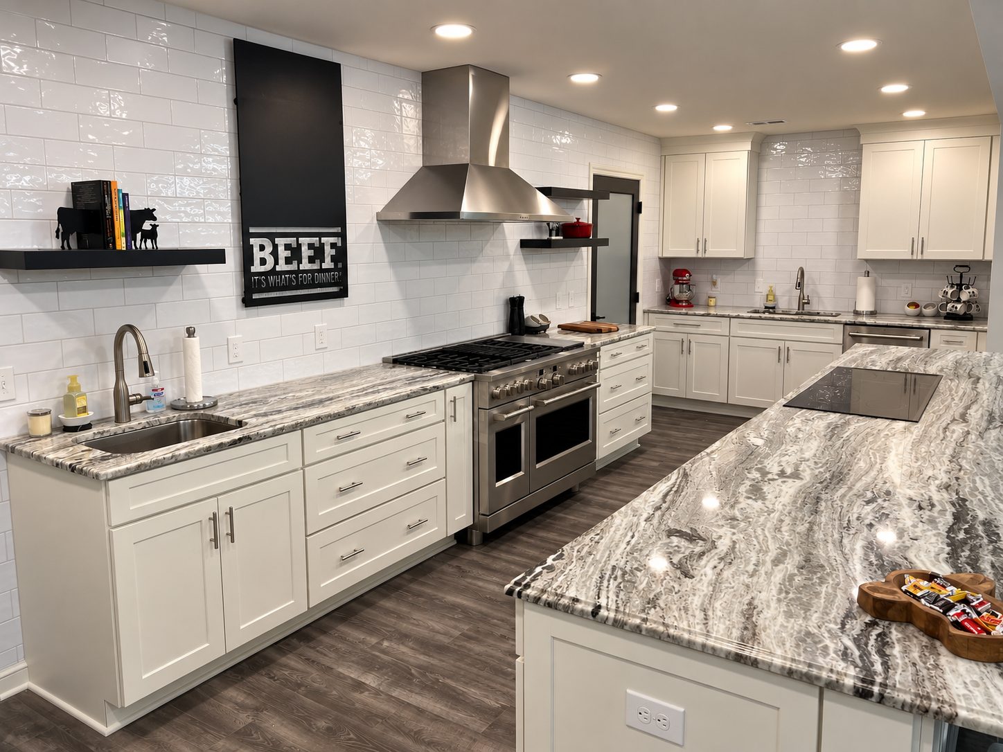 White farmhouse kitchen with subway tile, stainless range, and waterfall quartz island